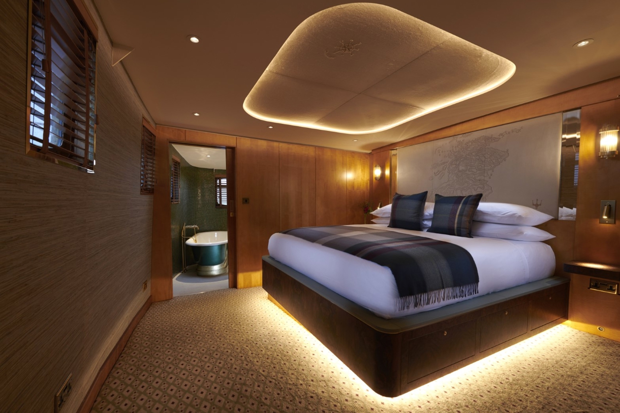 Skerryvore Hotel Suite aboard Fingal Hotel in Edinburgh featuring a super king-size bed with tartan accents, warm lighting, and an en-suite bathroom with elegant design.