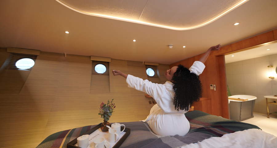 Girl stretches, getting out of bed, with both arms in the air