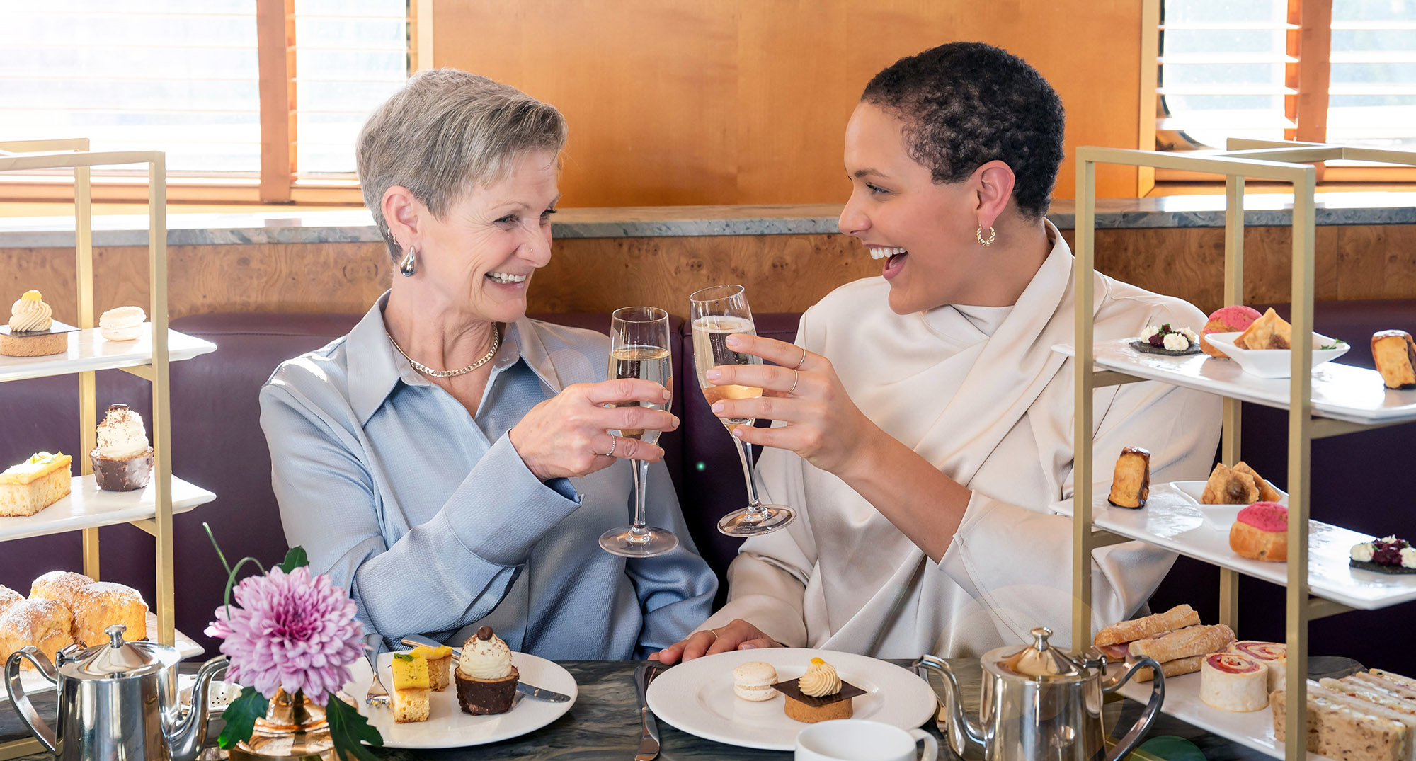 Mother and daughter enjoy Afternoon Tea as they toast each other with a glass of Champagne