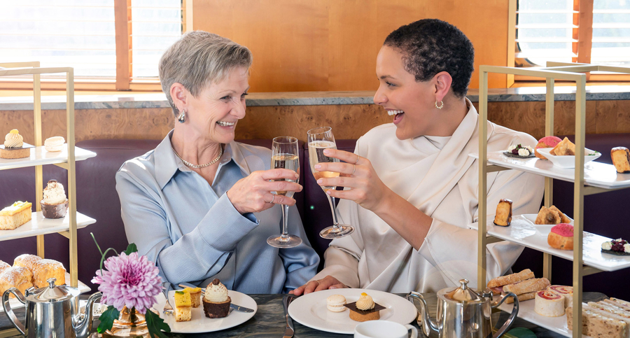 Mother and daughter enjoy Afternoon Tea as they toast each other with a glass of Champagne