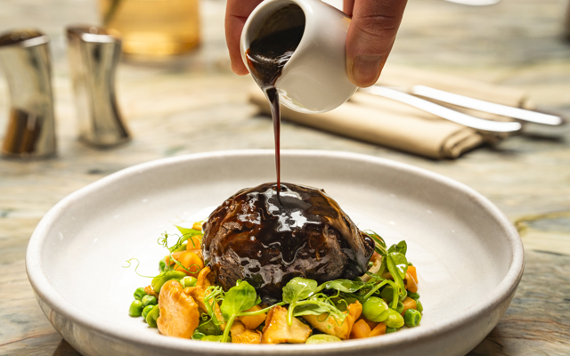 A main course dish of braised Inverurie beef cheek, chanterelles, peas, carrots, sauce périgourdine. 