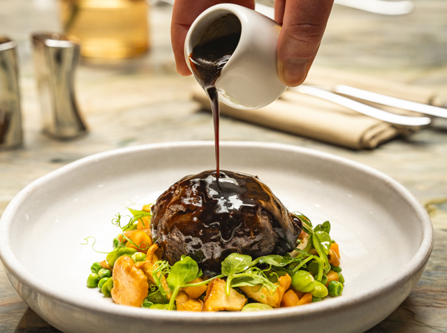 A main course dish of braised Inverurie beef cheek, chanterelles, peas, carrots, sauce périgourdine.