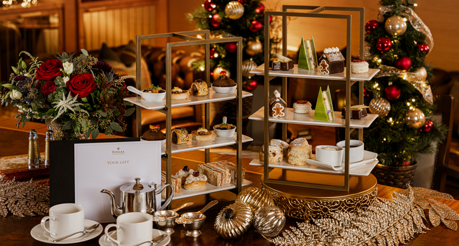 Afternoon tea on Fingal Hotel Edinburgh with tiered stands of cakes, pastries & sandwiches, with Christmas decorations and gift vouchers on the table.