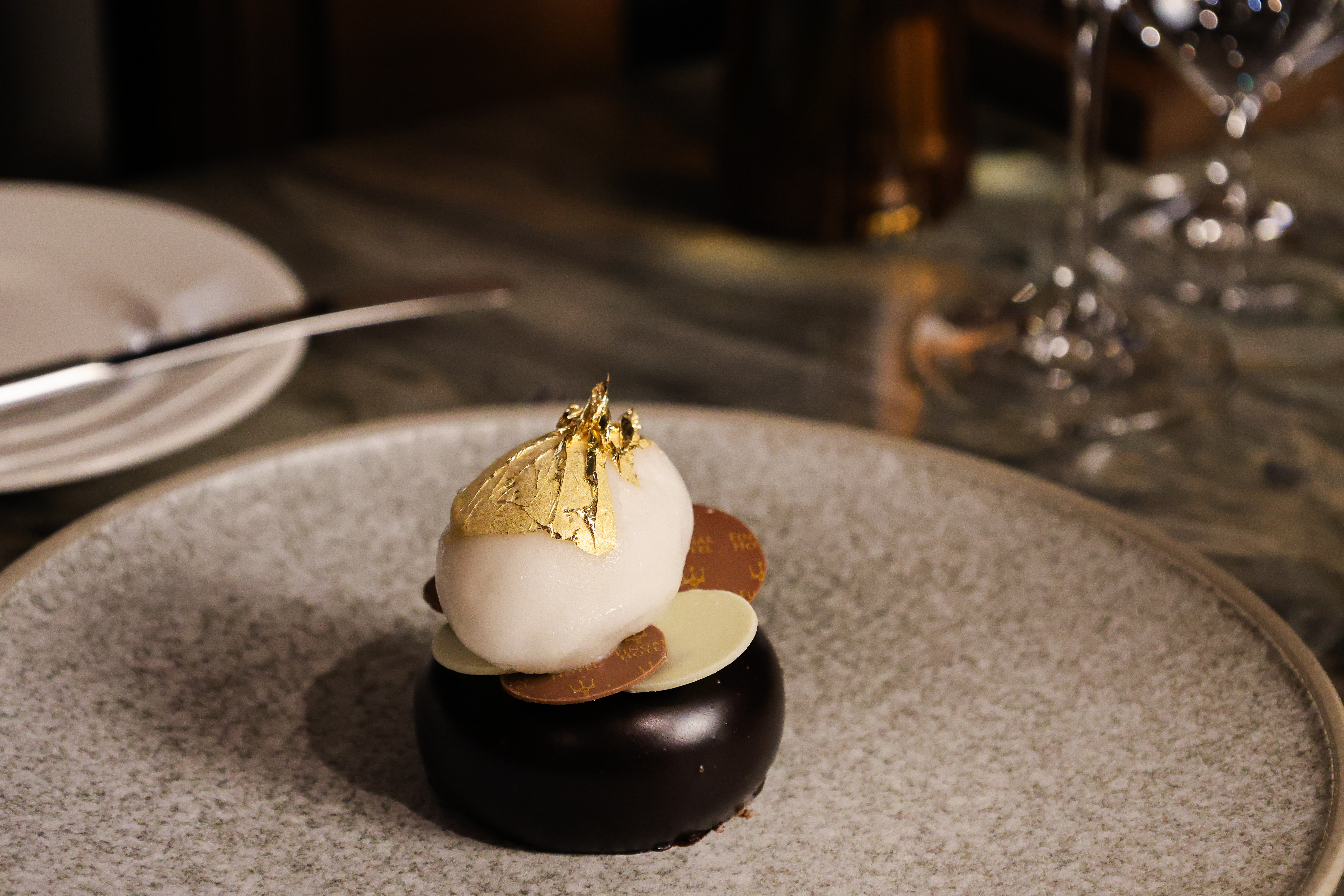 Chocolate dessert on a plate with gold leaf on top 