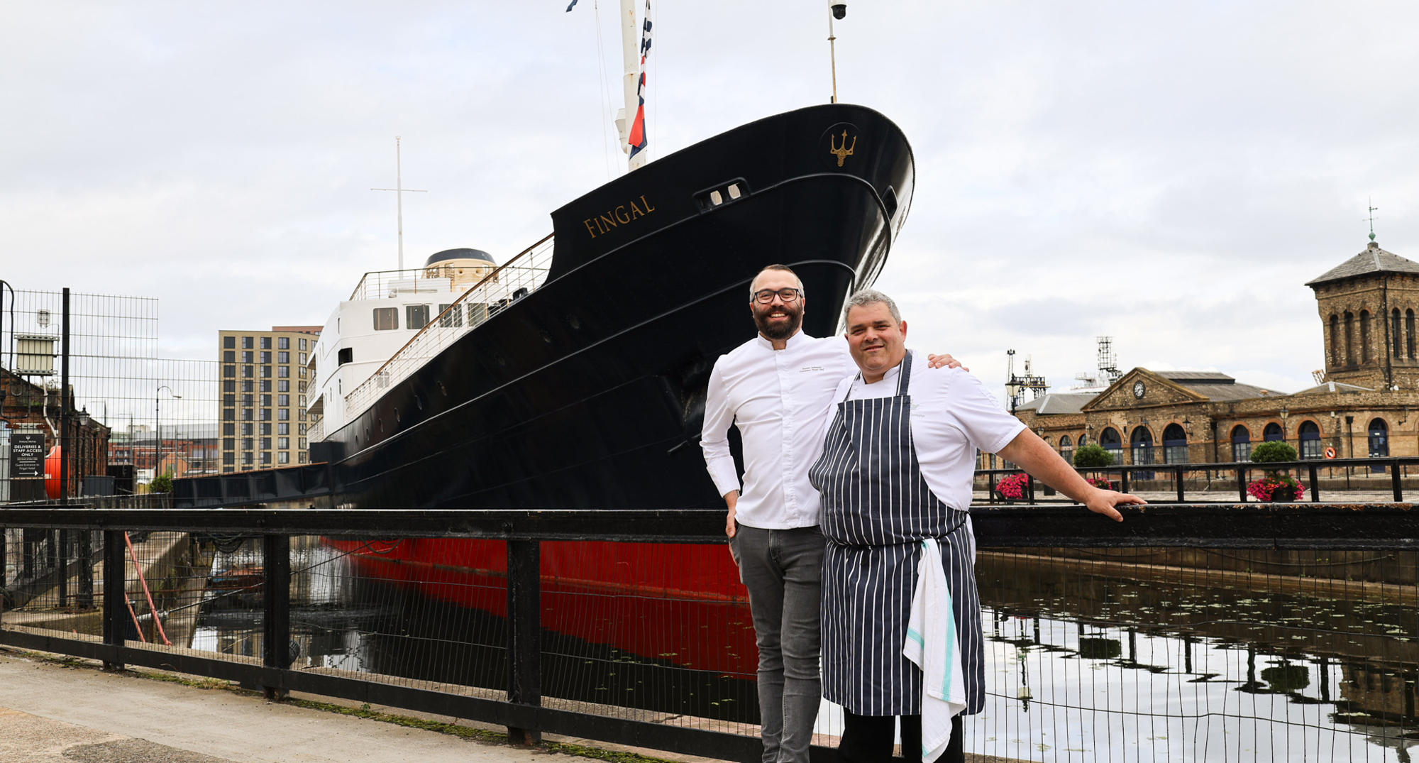 Two chefs in front of a ship 