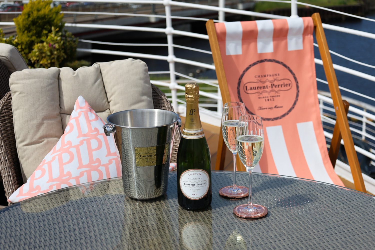 Two glasses of champagne and a bottle on a ship deck. 