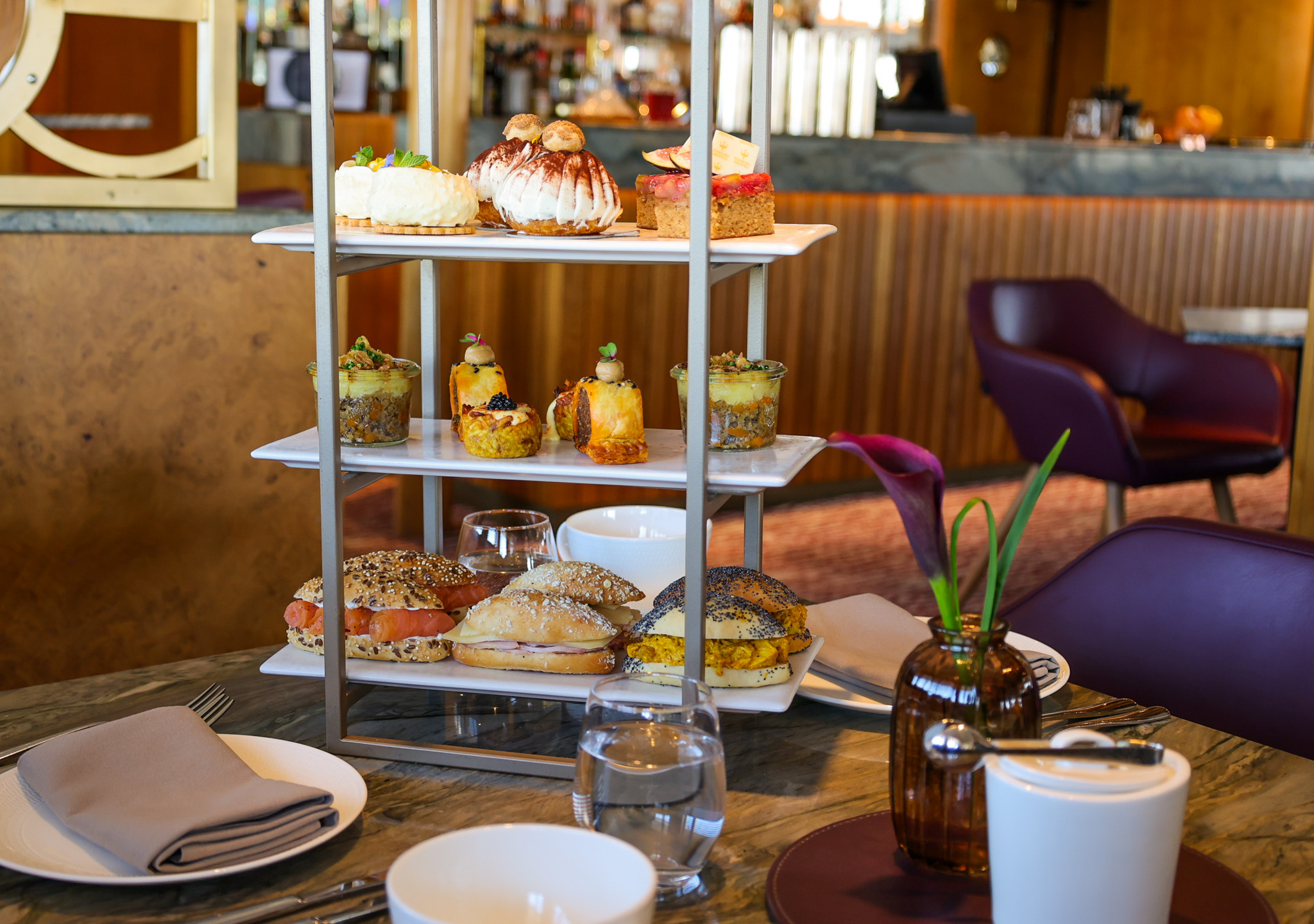 Afternoon tea stand with pastries, sandwiches, and desserts on a café table.