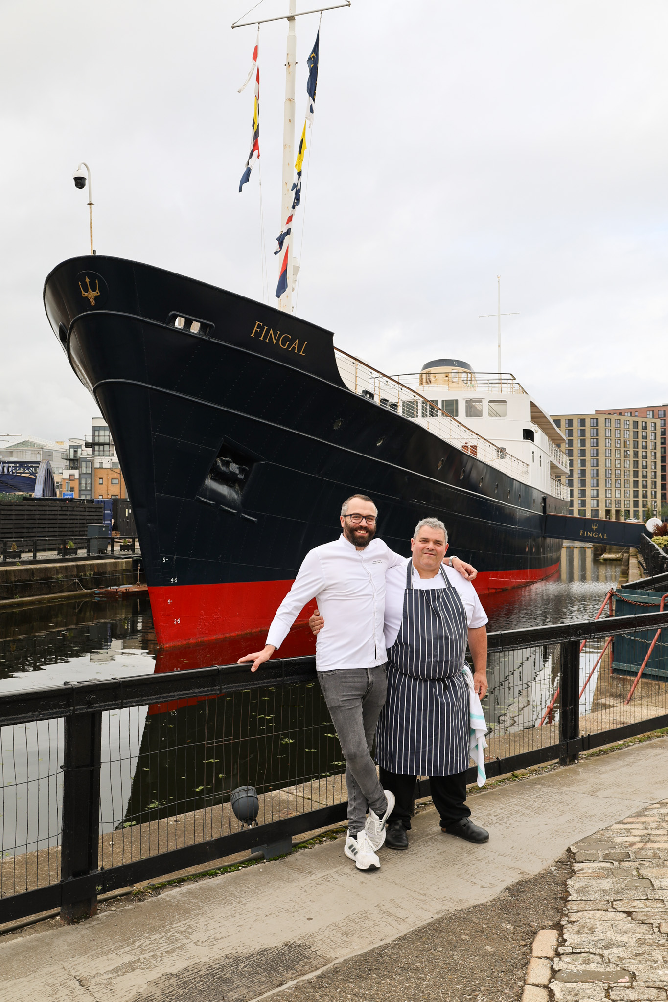 Two chefs standing in front of a ship.