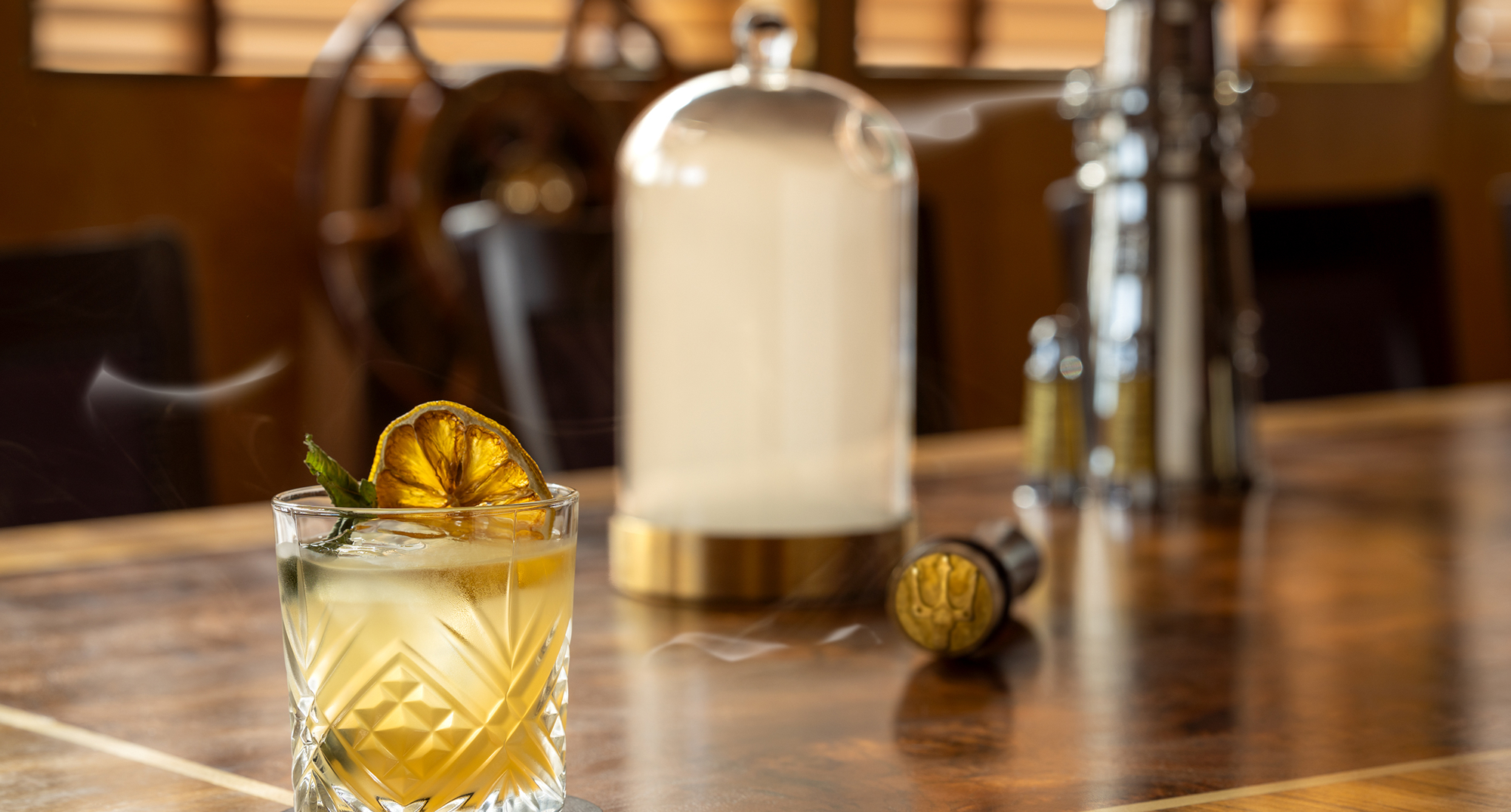 A cocktail in a whisky tumbler served next to a smoke cloche at Fingal Hotel. 