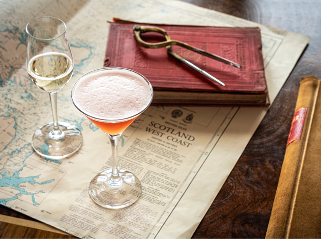 A cocktail sitting on a map with navigational instrument.