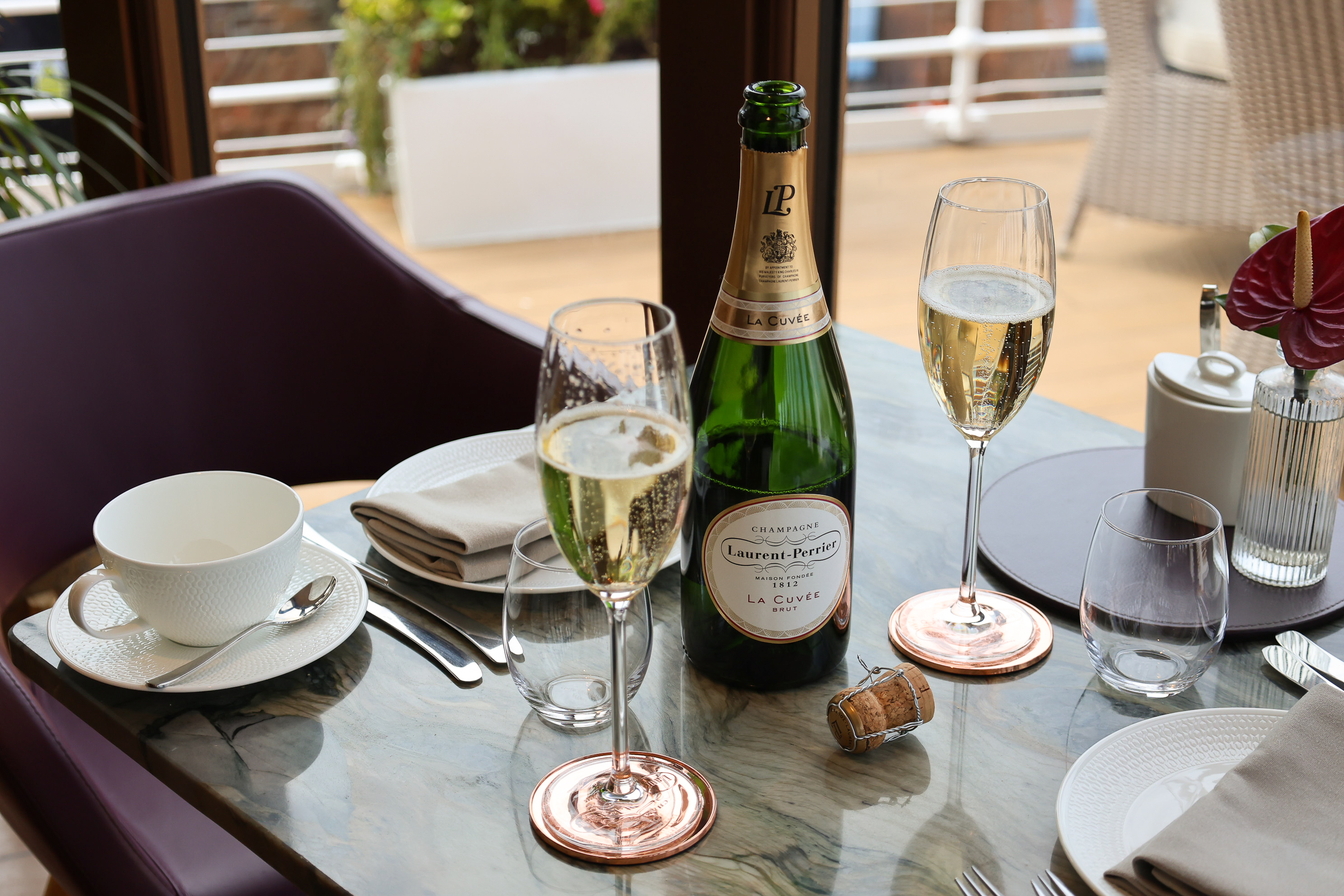 two glasses of champagne and an open bottle on the table.