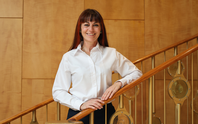 Woman standing on a stairs in white blouse and trousers.