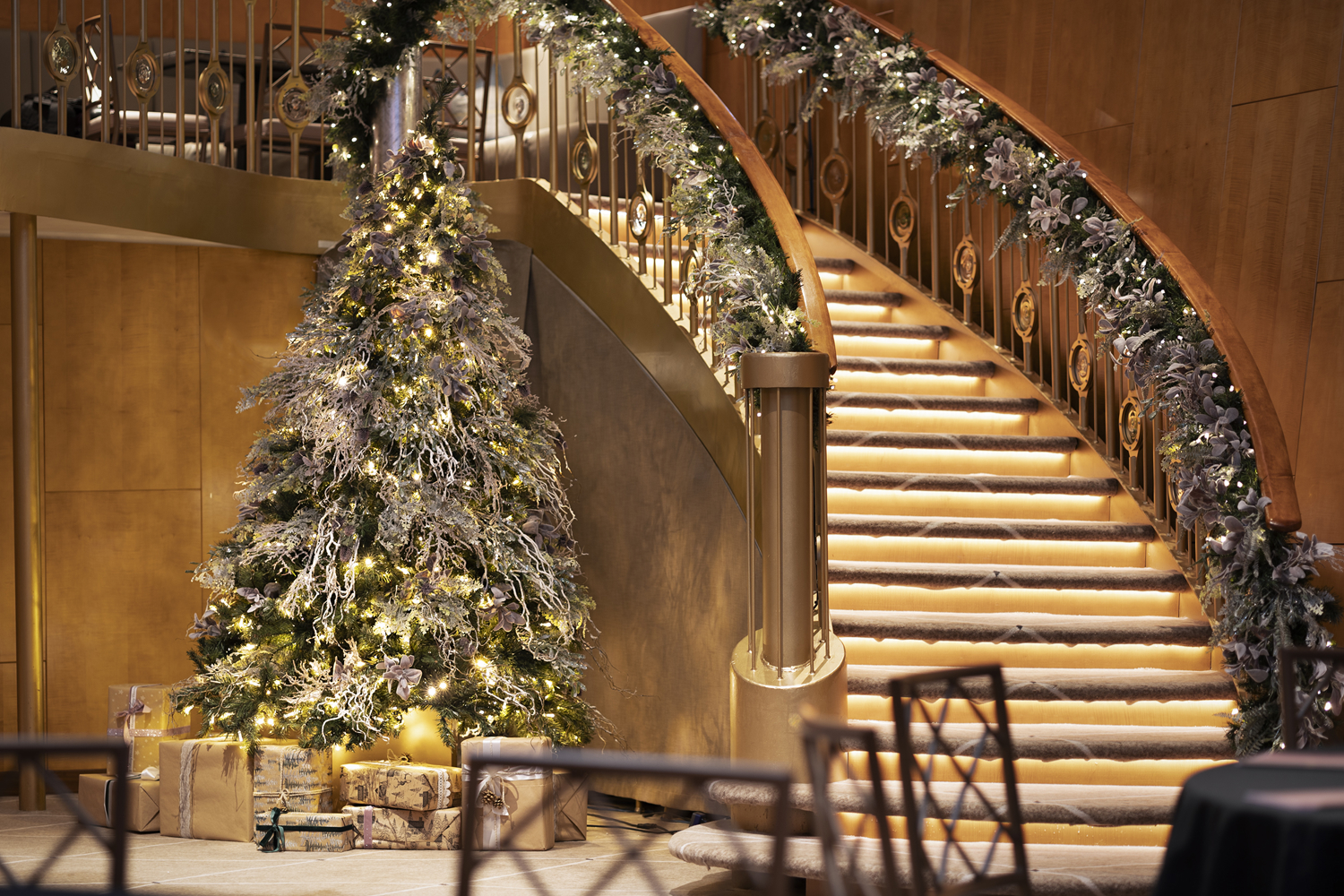 A Christmas tree next to a sweeping staircase in Fingal's Ballroom. There is a garland around the staircase bannister. 